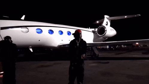 a man in a red bandana stands in front of a private jet with the letters n929u on it