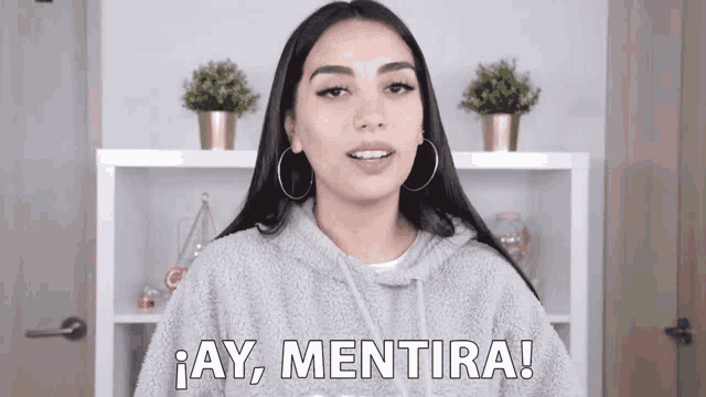 a woman wearing a grey hoodie says ay mentira