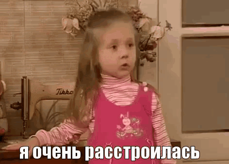 a little girl in a pink dress is standing in front of a sewing machine .