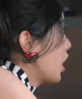 a close up of a woman 's ear with red heart shaped earrings