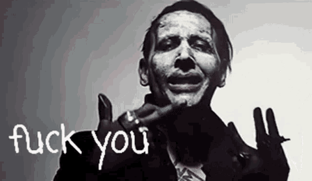 a man with white paint on his face is making a funny face and giving the middle finger .