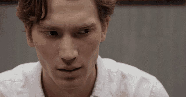 a man in a white shirt looks at the camera