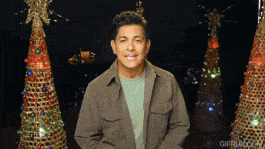 a man standing in front of a christmas tree with gifrun.com in the corner