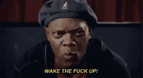 a man wearing a beret and a black jacket is making a funny face and saying wake the fuck up .