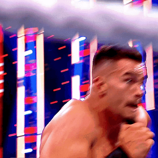 a man without a shirt is singing into a microphone with a blurry background