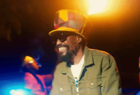 a man with a beard wearing a hat and sunglasses is smiling