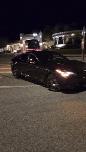 a black sports car is parked in front of a building at night