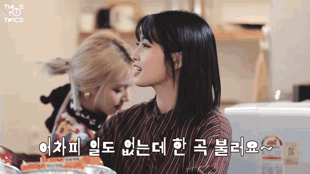 two girls are standing next to each other in a kitchen and one of them is wearing a striped shirt
