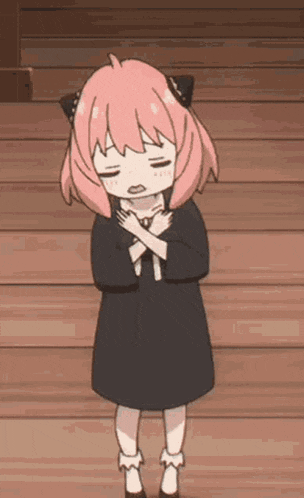 a little girl with pink hair is standing on a wooden floor with her eyes closed and her hands on her chest .