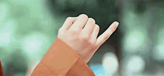 a person 's hand is making a heart shape with their index finger .