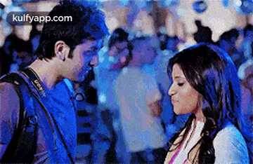 a man and a woman are kissing in front of a crowd of people .