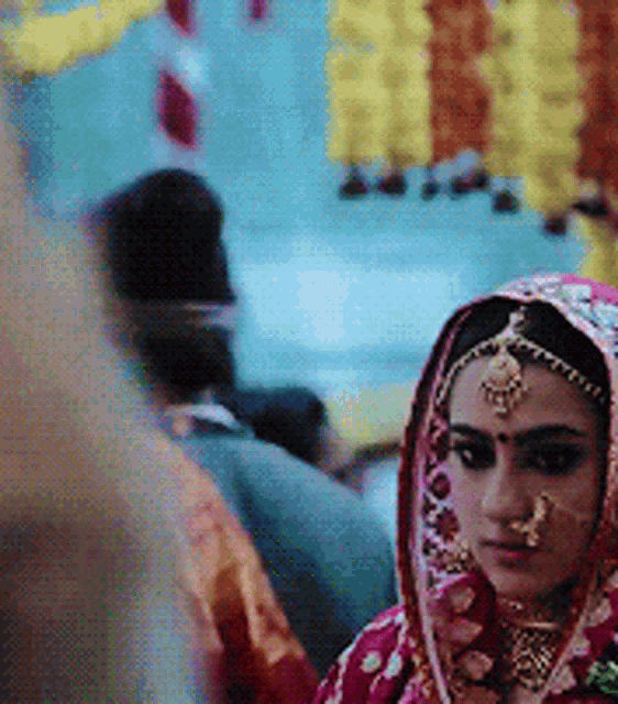 a woman wearing a veil and a nose ring looks at the camera