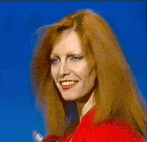 a woman with red hair and red gloves is holding a red object