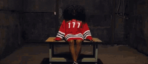 a woman is sitting on a bench in a dark room with her legs crossed .