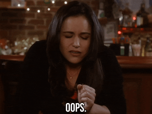 a woman sitting at a bar with her hands folded and says oops