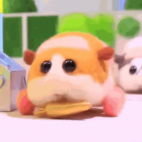 a stuffed hamster is eating a piece of food .