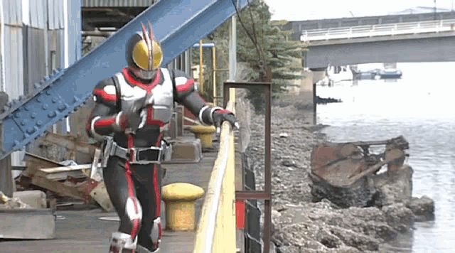 a man in a kamen rider costume is standing next to a railing .