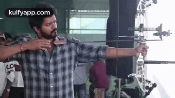 a man in a plaid shirt is holding a bow and arrow in his hands .