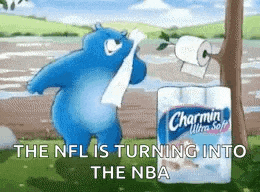 a blue teddy bear is holding a roll of toilet paper next to a roll of charmin toilet paper .