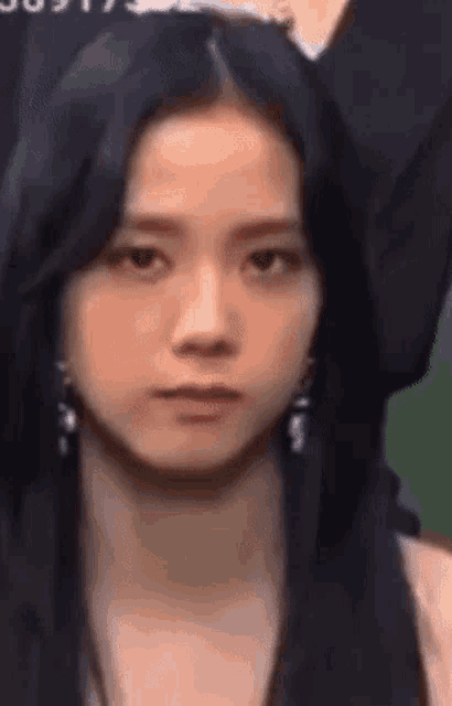 a close up of a woman 's face wearing earrings and looking at the camera .