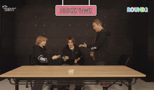 three people sitting at a table with a sign that says " judge time "