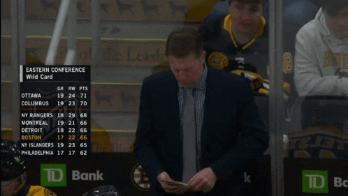 a man sits in the stands looking at a scoreboard for the eastern conference