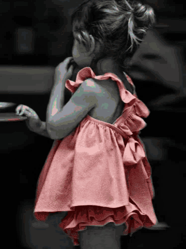 a little girl wearing a pink dress with ruffles