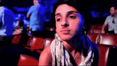 a man with a scarf around his neck is sitting in a stadium