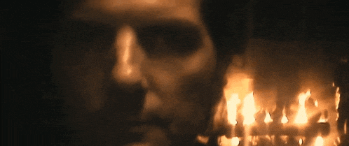 a close up of a man 's face with candles behind him .