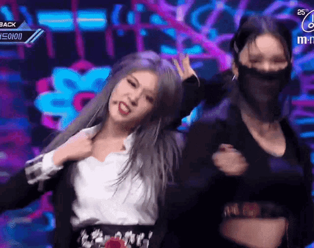 two women are dancing on a stage and one has a mask on her face .