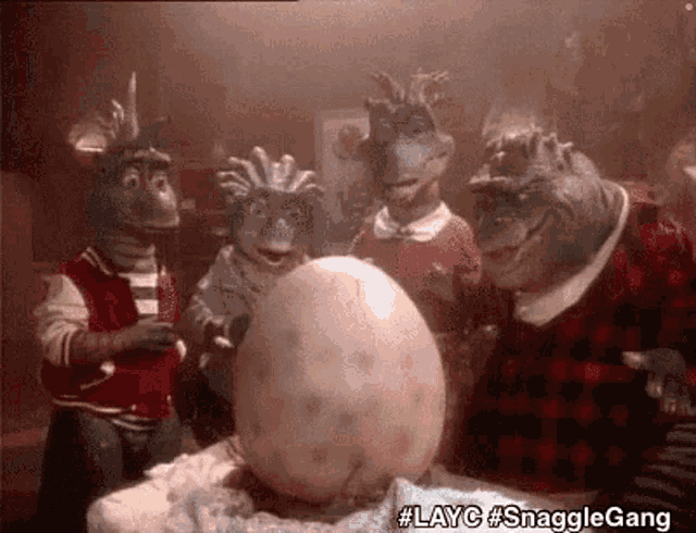 a group of dinosaurs are standing around a giant egg .