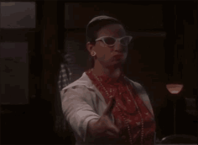 a woman wearing sunglasses and a scarf is giving a thumbs up