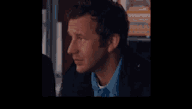 a man wearing a blue shirt and a black jacket