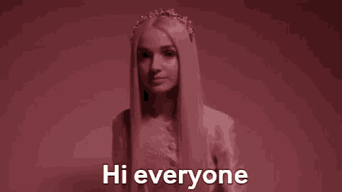 a woman with long blonde hair is wearing a flower crown and saying hi everyone .
