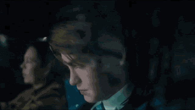 a man is sitting in the back seat of a car looking out the window .