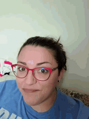 a woman wearing red glasses and a blue shirt that says ' uc ' on it