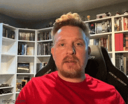 a man in a red shirt is sitting in a gaming chair in front of a bookshelf ..