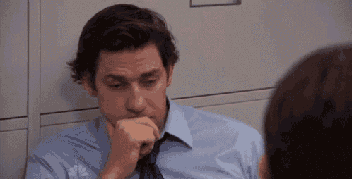 a man in a blue shirt and tie is sitting in a filing cabinet with his hand on his chin .