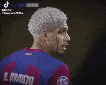 a soccer player with white hair is standing in front of a purple background .