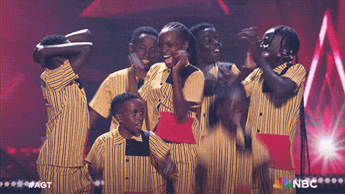 a group of people in yellow and black striped shirts are standing on a stage .