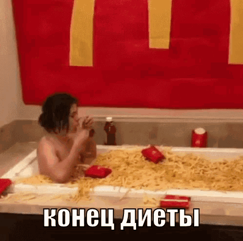 a woman is sitting in a bathtub filled with french fries and drinking a soda