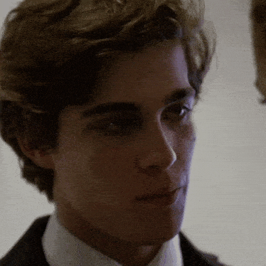 a close up of a young man in a suit and tie looking at the camera .