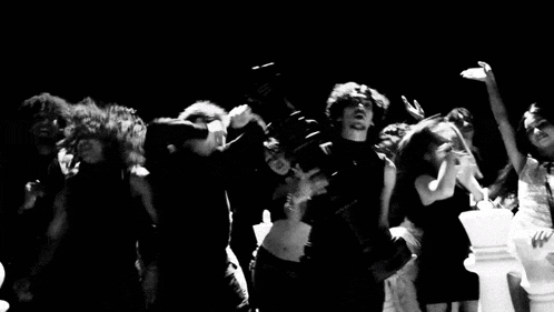 a group of people are dancing in a dark room