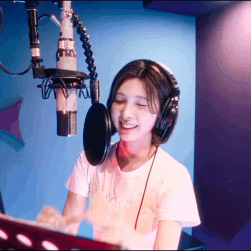 a woman wearing headphones is singing into a microphone in a recording studio