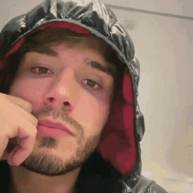 a man with a beard is wearing a hooded jacket with a red lining