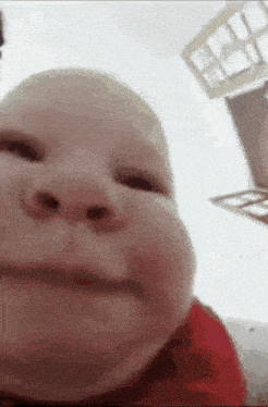 a close up of a baby 's face making a funny face while looking at the camera .