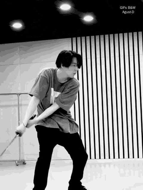 a black and white photo of a man holding a sword with the words gifs b & w agust d on the bottom right