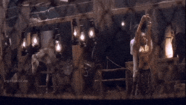 a man and a woman are kissing in a stable with horses in the background .