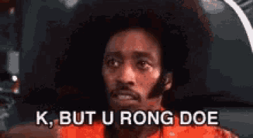 a man with an afro is sitting in a car and saying `` k but u rong doe '' .