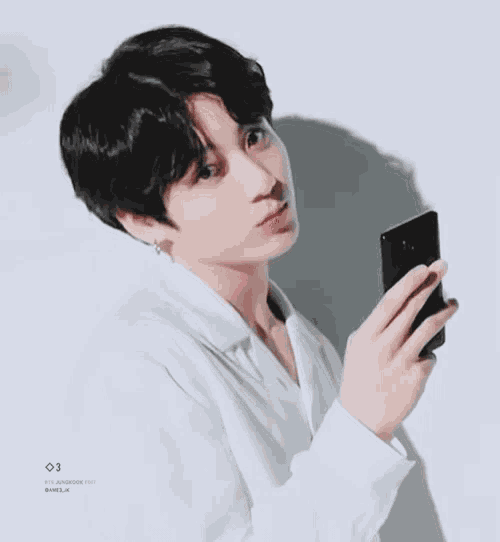 a young man is holding a cell phone in his hand .